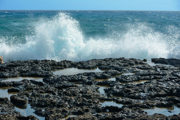 Waves with splashes roll onto rocky shore