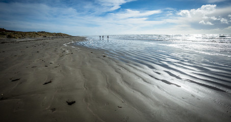 Sandy beach with tide receeding, reflective sandy shore
