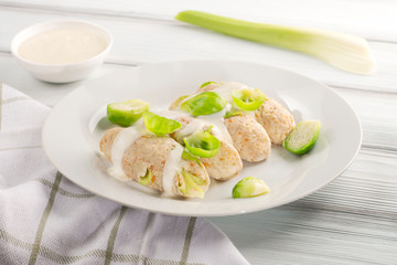 Tasty chicken cutlets with cabbage and carrots with sour cream sauce on a white plate