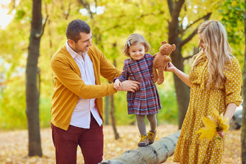 Fototapeta premium Content girl with parents walking in autumn park