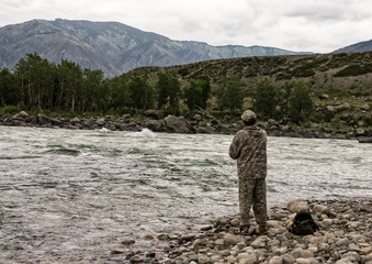 single fisherman on a stormy river is fishing on a sunny summer day