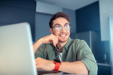 Handsome man smiling while working on laptop