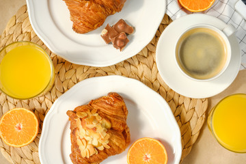 Coffee with croissants, pieces of chocolate, orange juice and tangerines for breakfast