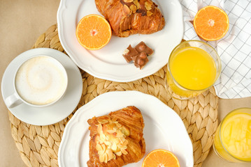 Coffee with croissants, pieces of chocolate, orange juice and tangerines for breakfast