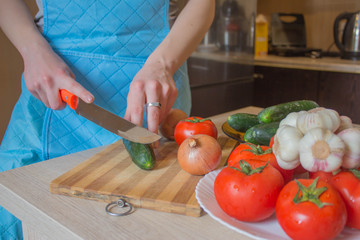 Woman's hands cutting pepper, behind fresh vegetables. Woman cook at the kitchen. Chef cuts the vegetables into a meal. Preparing dishes