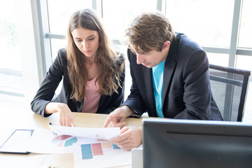 Business colleagues having meeting in the home office, or two young coworkers working review data sheet at modern office, businessman  Ask the status of the project.