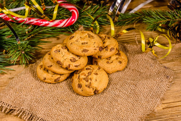 Pile of the chocolate chip cookies on sackcloth in front of christmas decorations
