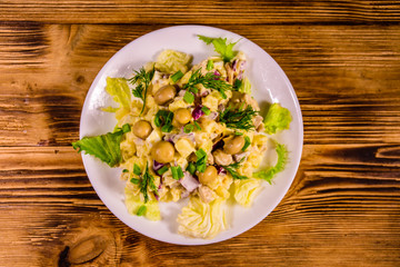 Salad with marinated mushrooms, eggs, red onion, boiled potato and mayonnaise on wooden table. Top view