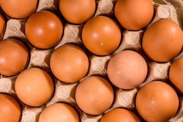 Pile of the hen eggs in paper tray on wooden table. Top view