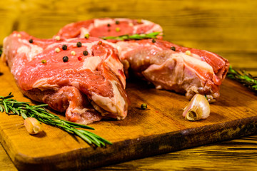Raw ribeye steak, spices, rosemary and garlic on cutting board