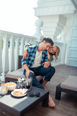 Wife hugging man while having breakfast on balcony