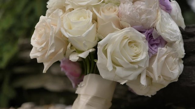 Close up tilt down on bride’s bouquet outside on rocks