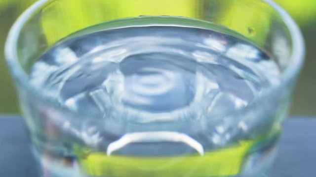 Vibration of water in a glass cup close up. Slow motion