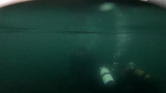scuba divers exploration of a mountain lake. slow motion. bad weather diving, ice water