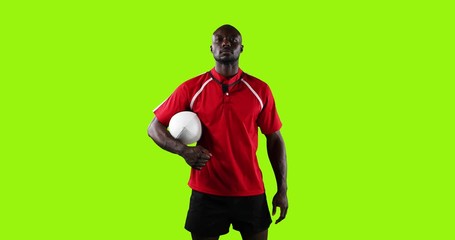 Professional rugby player standing and holding a ball on green background 4k