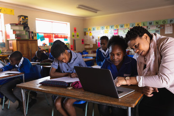 Teacher helping schoolchildren in a lesson at a township school