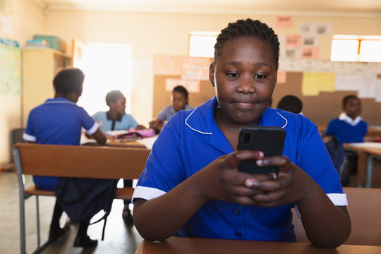 Schoolgirl using smartphone in classroom at a township school