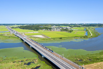 Obraz premium 千葉県の印旛沼を渡る京成スカイライナーと国道464号線を俯瞰撮影