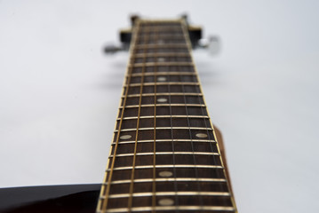 Guitar fretboard close-up top view of the neck of the guitar and strings on white isolated background. Acoustic guitar perspective along fretboard