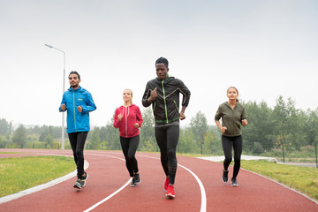 Group of young intercultural sportsmen and sportswomen running marathon
