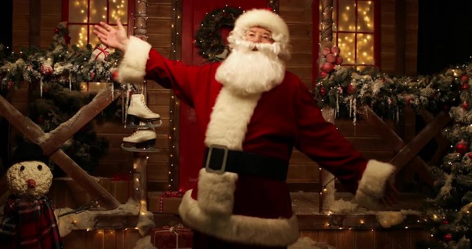 Santa Claus is dancing near in the yard near his house  decorated for Christmas. Christmas and New Year time. 