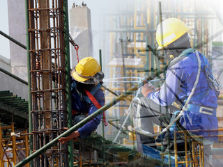 Construction workers working on scaffolding with blue sky at construction site