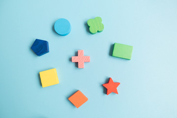 Top view Colorful Wooden building blocks with different shapes for developing and entertainment of Children on blue background.