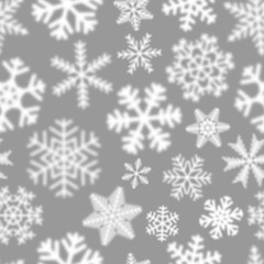Christmas seamless pattern of white defocused snowflakes on gray background