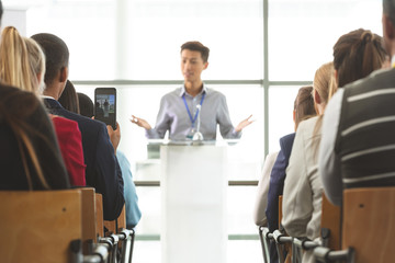 Businessman taking photo with mobile phone during seminar 