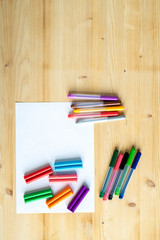 Overview of wooden table background with blank paper and crayons