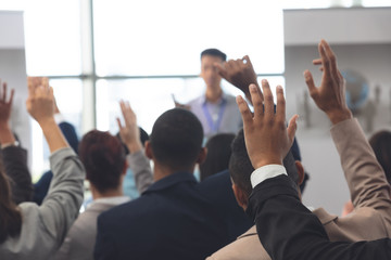 Business people raising hands in a business seminar