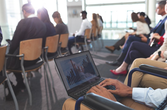 Disabled young businessman using laptop during seminar