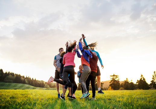 Large group of fit and active people jumping after doing exercise in nature.