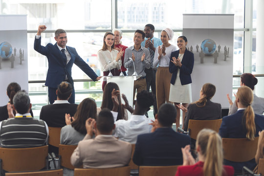 Businessman standing at podium with colleagues and speaks in a business seminar