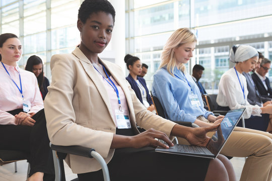 Businesswoman with laptop looking at camera in seminar
