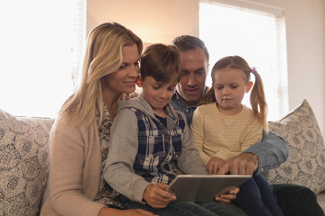 Family using digital tablet together in living room
