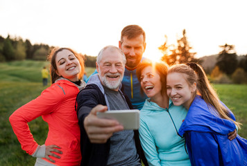 A group of fit and active people resting after doing exercise in nature, taking selfie. - Powered by Adobe