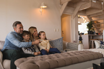 Family watching television in living room at home