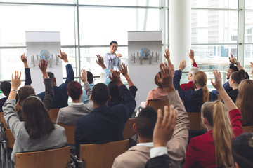 Business people raising hands in a business seminar