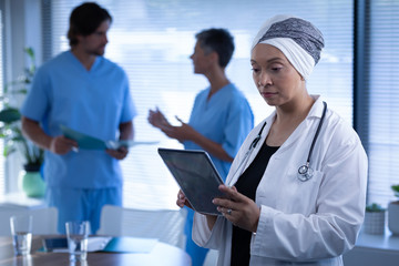 Fototapeta premium Female doctor looking at digital tablet in clinic at hospital