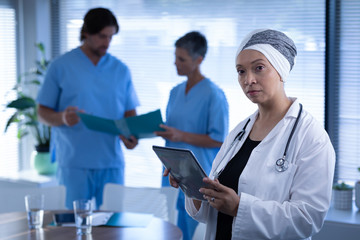 Matured female doctor standing in clinic while holding digital tablet