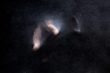 Man hand in black textured background. Abstract photo.