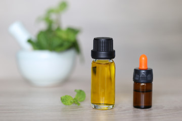 Peppermint essential oil in glass bottles on wooder background