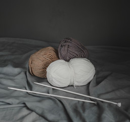 The yarn is beige, brown, gray and white. The background is aged wood. Knitting needles. Autumn hobbies