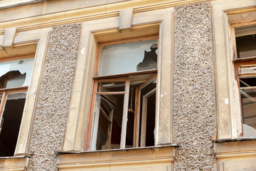 broken glass in the windows of an old settled and abandoned town house