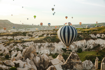 Goreme, Turkey / May, 2019 - Numerous hot air balloons all lift into the air just after dawn