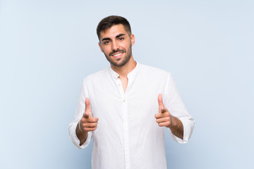 Fototapeta premium Handsome man with beard over isolated blue background pointing to the front and smiling