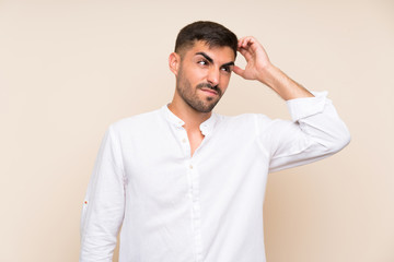 Handsome man with beard over isolated background having doubts and with confuse face expression