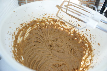 Brown cake batter in a white bowl whisked with a nice pattern and a kitchen mixer