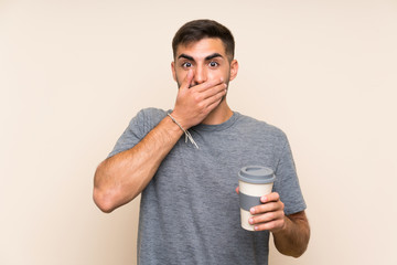 Handsome man with beard holding a take away coffee over isolated background with surprise facial expression